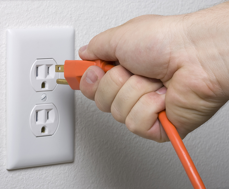 plugging in an orange cord to outlet
